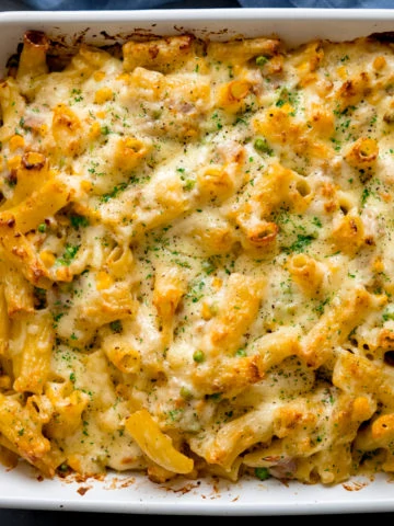 Overhead image of tuna pasta bake in a white dish topped with finely chopped parsley.