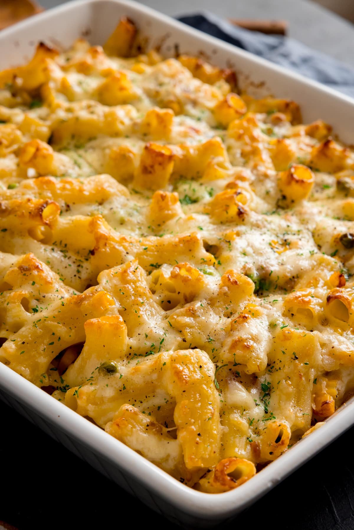 Close up of creamy tuna pasta bake in a white baking dish.