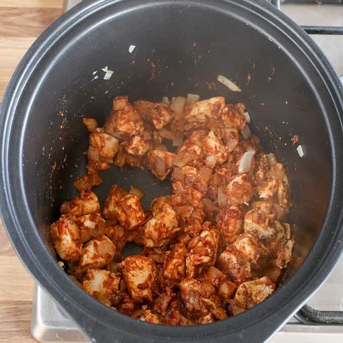 Chicken curry ingredients cooking in a pan before sauce is added.