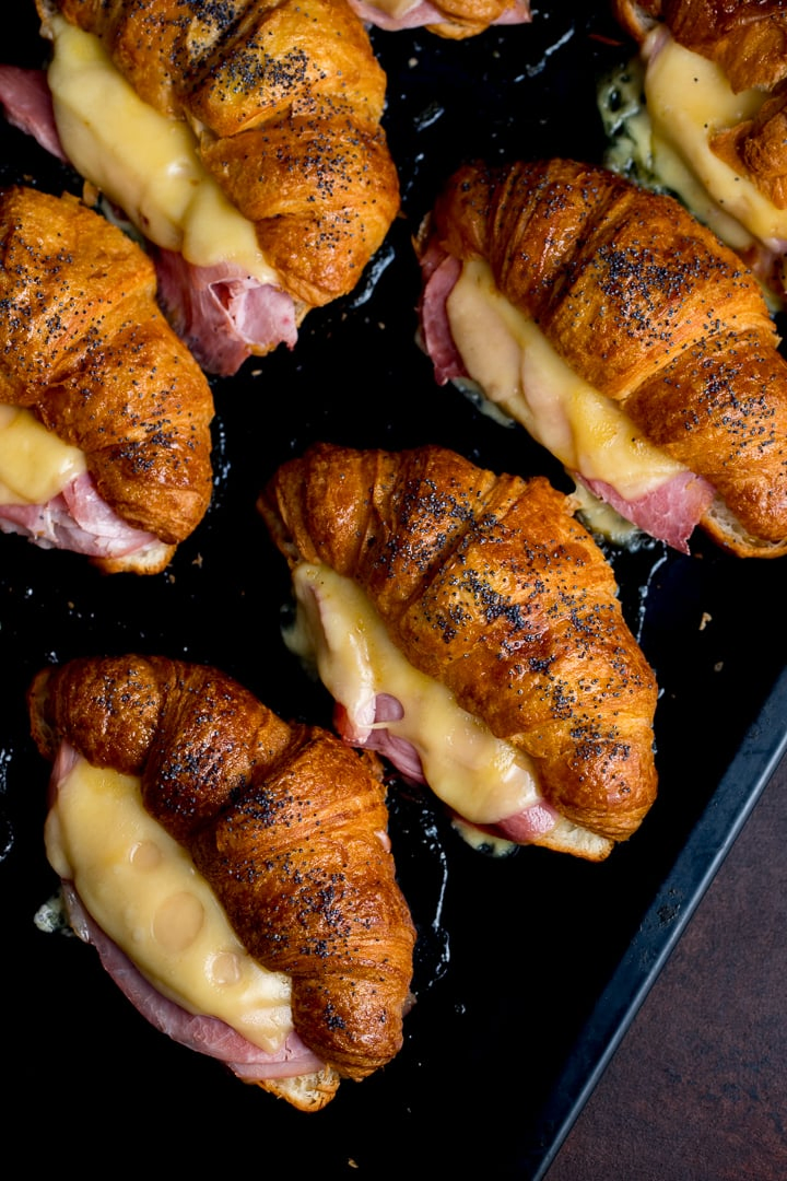 Overhead image of ham and cheese croissants on a dark tray