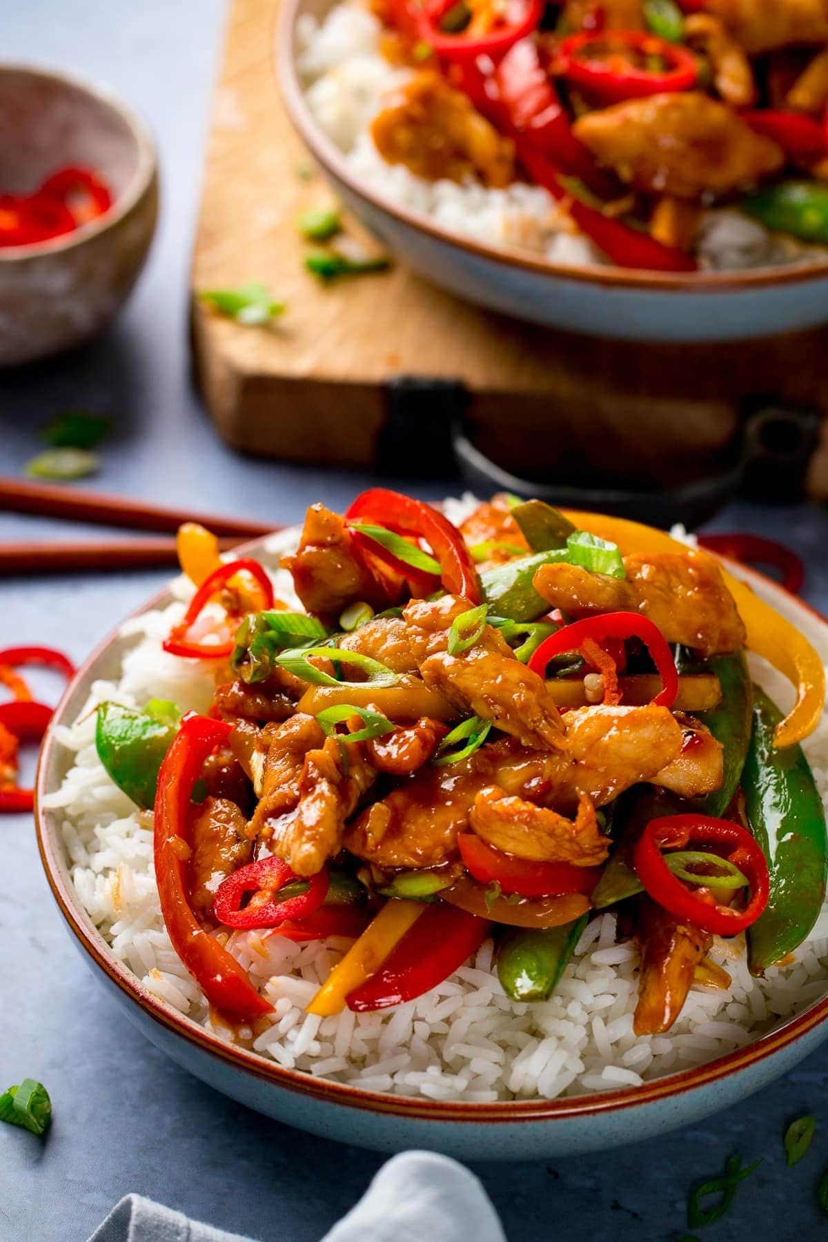 chicken stir fry on a bowl of boiled rice with a further bowl in background