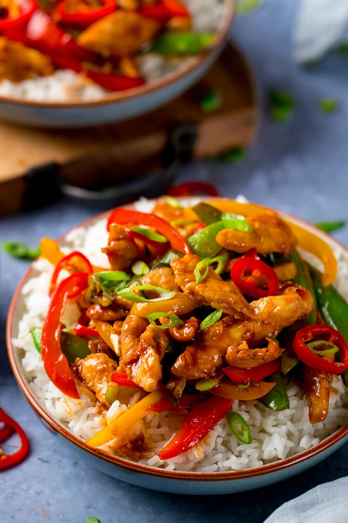 chicken stir fry with rice in a bowl topped with chillies and spring onions