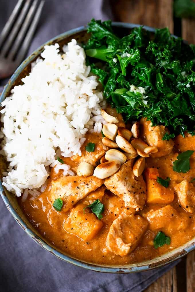 Ovehead photo of African Peanut and Chicken Stew in a stone bowl with boiled rice and kale