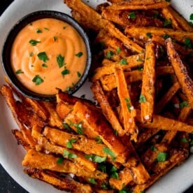 Carrot fries on a white plate with dipping sauce