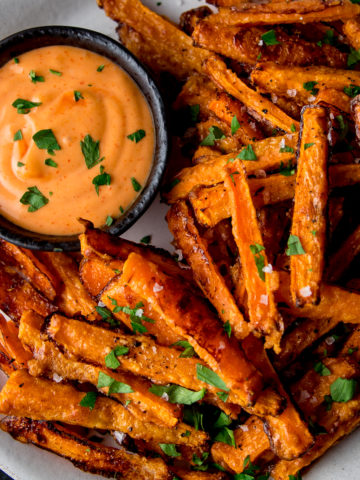 Carrot fries on a white plate with dipping sauce