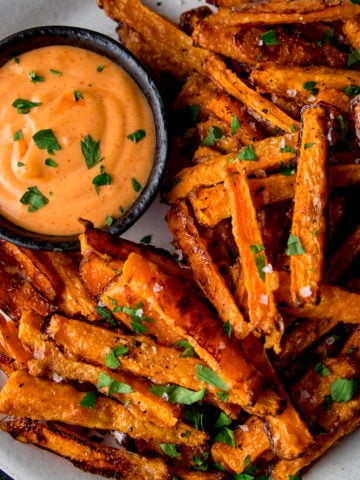 Carrot fries on a white plate with dipping sauce