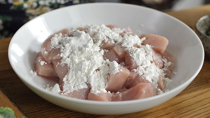 Chicken pieces in a bowl with seasoned cornflour
