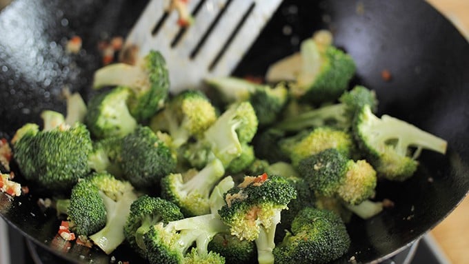 close up of broccoli frying in a work