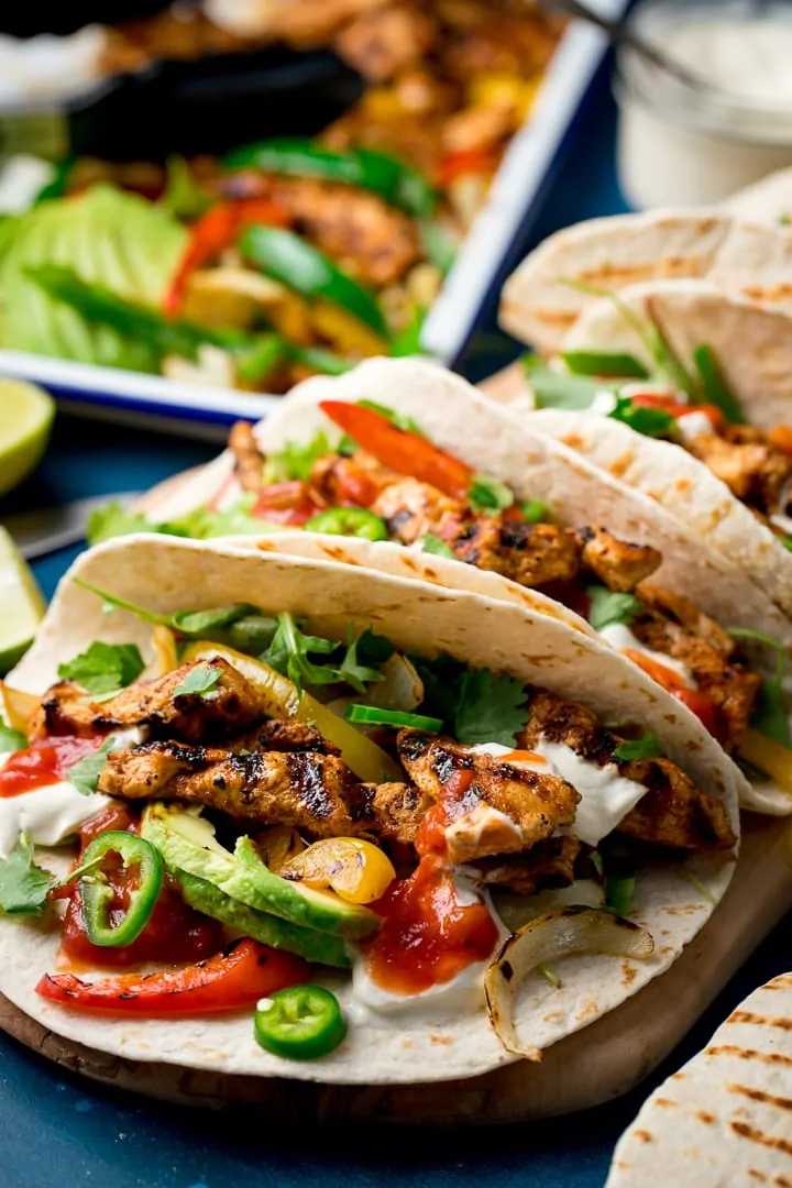Close up of an open chicken fajita with further fajitas in the background