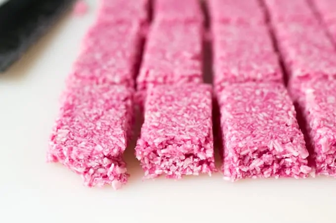 Raspberry Ruffle Bars - A vibrant coconut raspberry snack bar, covered in rich, dark chocolate.