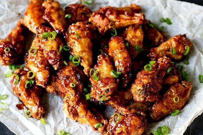 Overhead picture of Sticky and Crispy Asian Chicken Wings stacked up on grease proof paper.