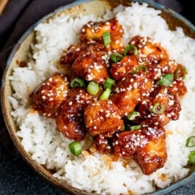 Crispy Sesame Chicken on a bed of rice in a stone bowl
