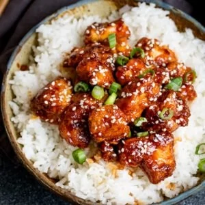 Crispy Sesame Chicken on a bed of rice in a stone bowl