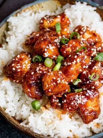 Crispy Sesame Chicken on a bed of rice in a stone bowl