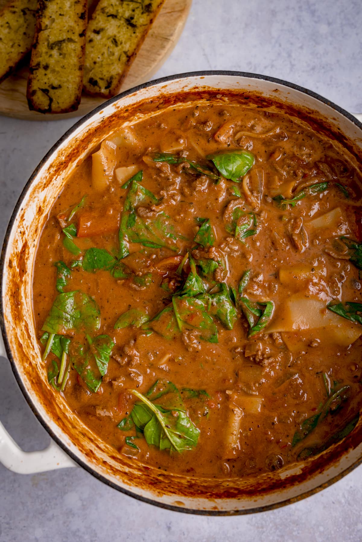 Overhead image of a white cast iron pan filled with lasagne soup before the cheese has been sprinkled on.