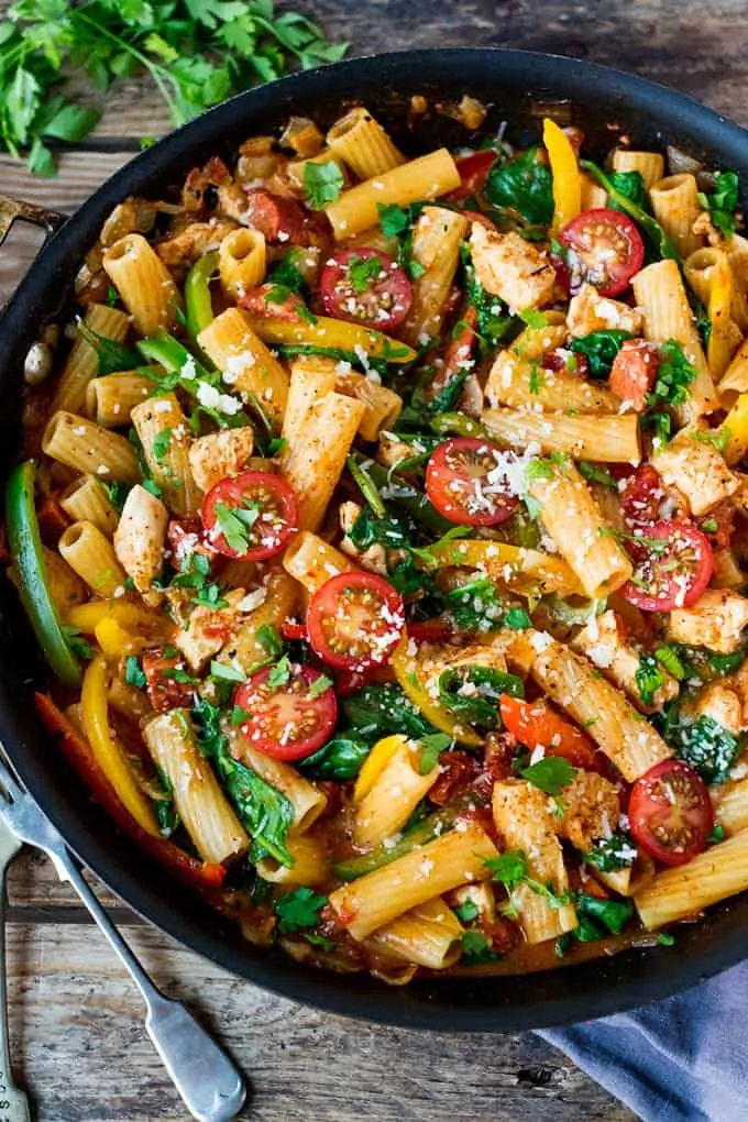 Cajun chicken pasta one pot in a blue pan with chopped cherry tomatoes