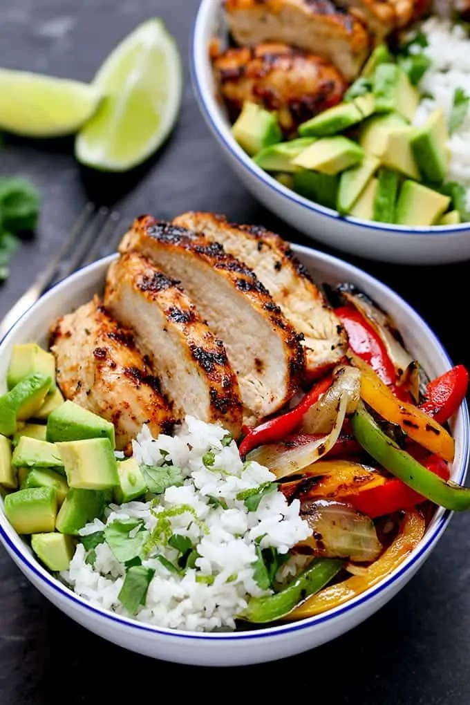 Close up photo of griddled Cajun chicken with charred veggies and coriander-lime rice in a bowl