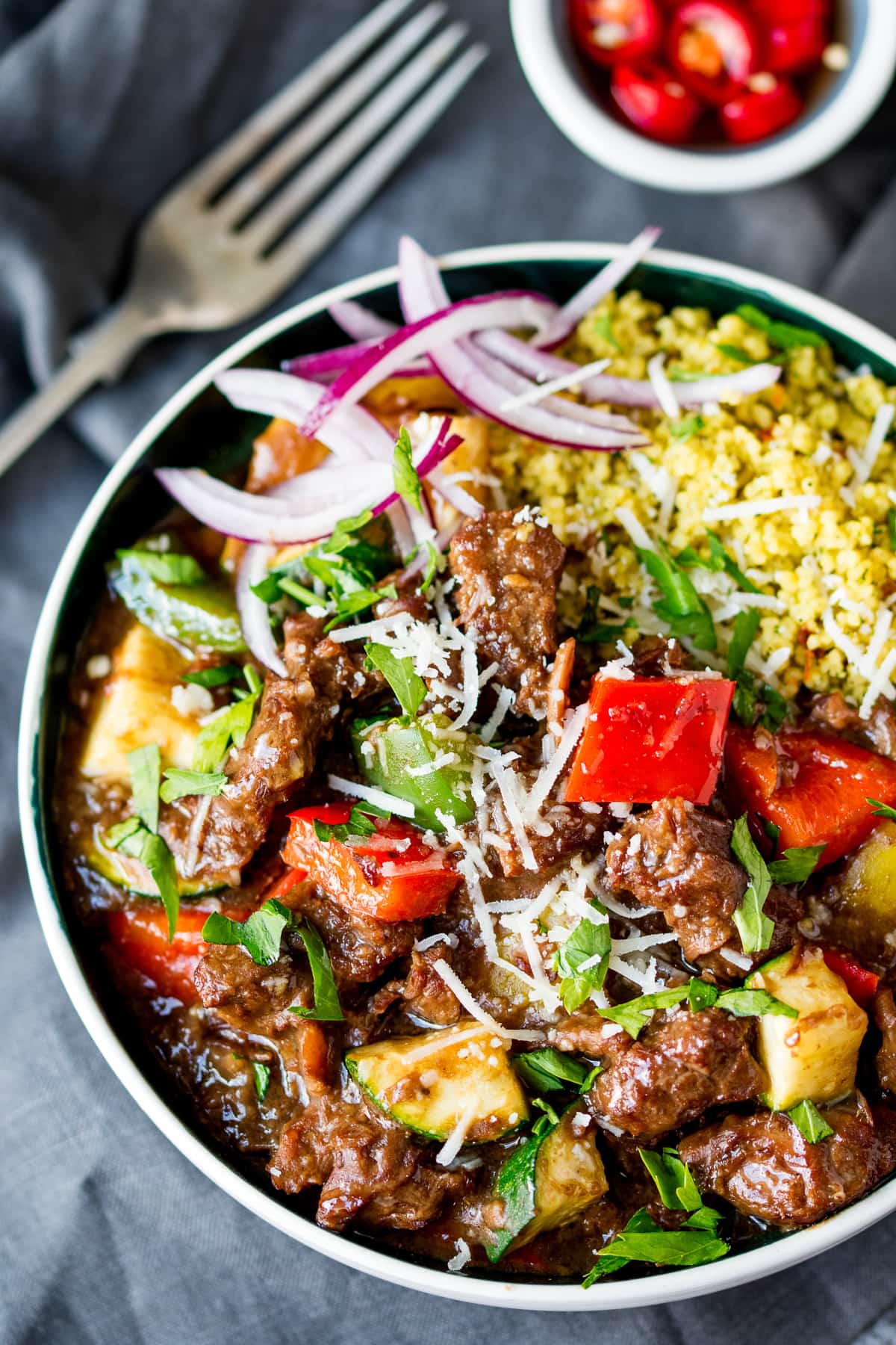 Slow Cooked Summer Beef Casserole in a bowl with couscous, red onions and parmesan.