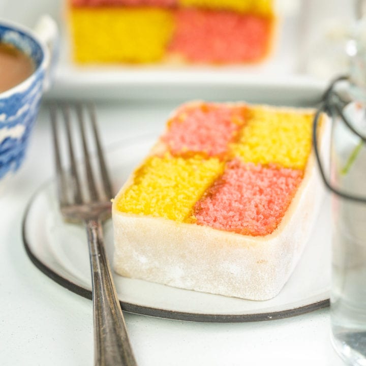 Battenberg cake slice on a plate with a fork on a light background.
