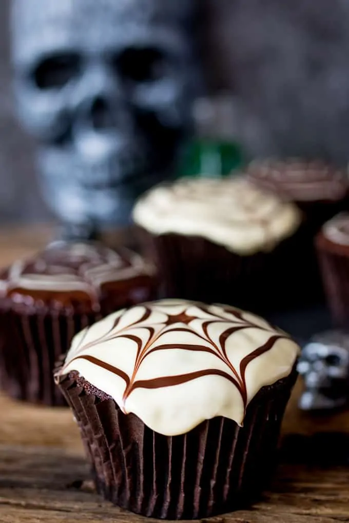 Close up of a chocolate Halloween cupcake with a spiderweb pattern on top.