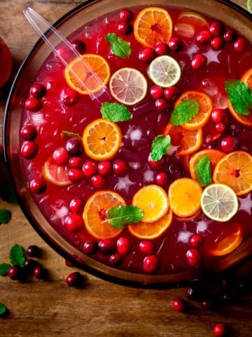 Square image of Festive Punch in a bowl topped with slices of citrus fruits and cranberries