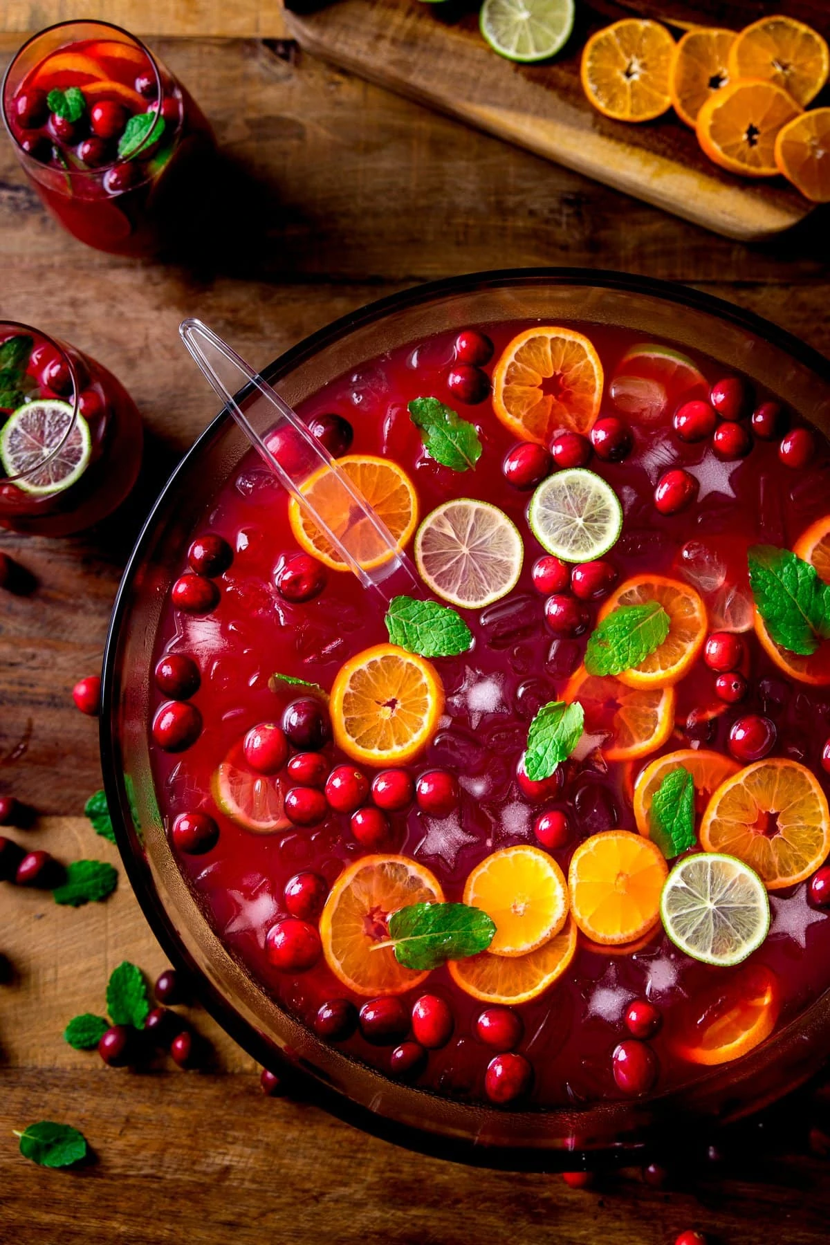 Festive Punch in a bowl on a wooden table. Punch is topped with slices of citrus fruits and cranberries