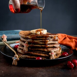 Maple Syrup being poured onto a stack of gingerbread pancakes.
