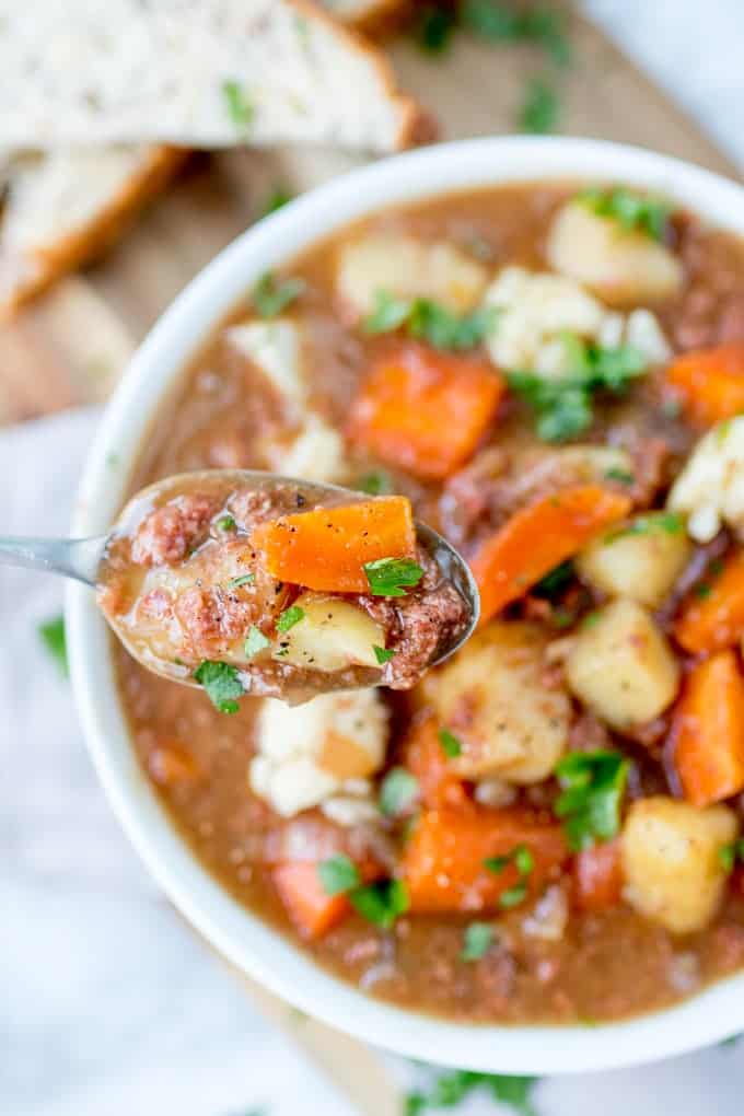 Overhead photo of a bowl of corned beef hash soup with a spoonful close to the camera.