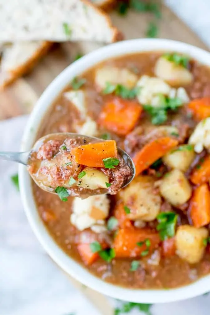 Overhead photo of a bowl of corned beef hash soup with a spoonful close to the camera.