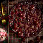 Chocolate Cherry Cake on a wire rack with cherries scattered around.