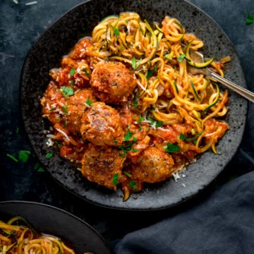 Square image of Turkey meatballs and courgetti on a dark plate