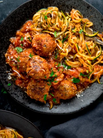 Square image of Turkey meatballs and courgetti on a dark plate