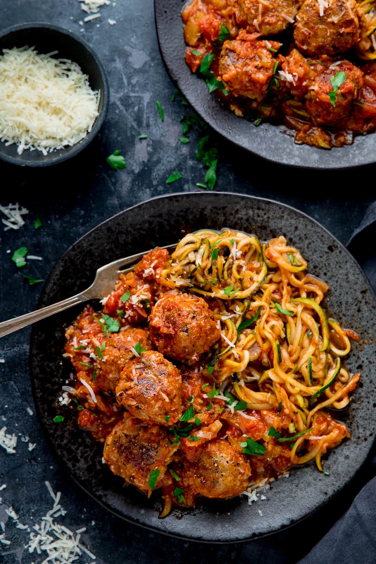 Turkey meatballs and courgetti on a black plate against a dark background
