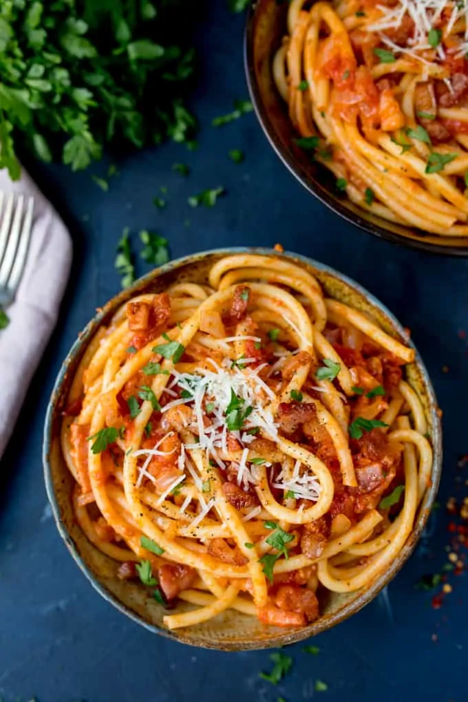 Overhead photo of a bowl of Amatriciana on a blue background