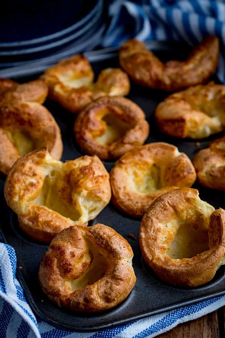 Yorkshire puddings in a tin with striped kitchen towel 