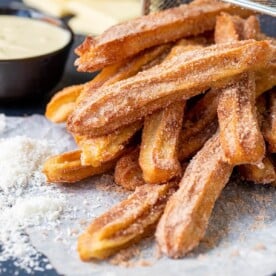 A pile of churros dusted with cinnamon sugar sat on their side.