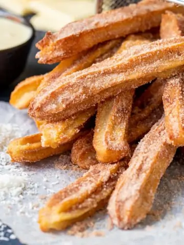 A pile of churros dusted with cinnamon sugar sat on their side.