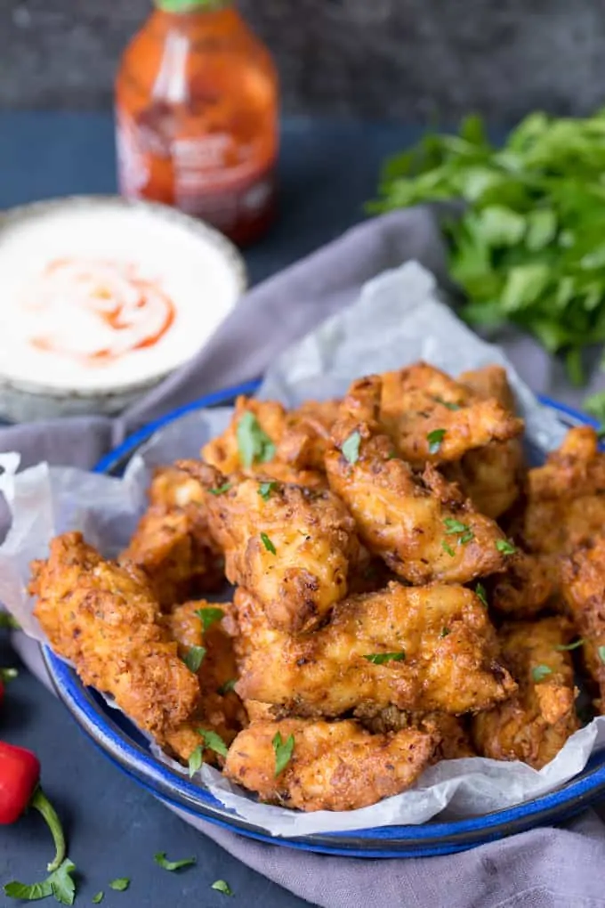 Crispy Chicken Tenders in a blue bowl with Garlic Chilli Dip in the background