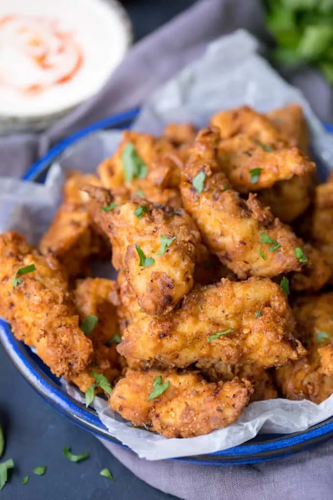 Crispy Chicken Tenders in a blue bowl sprinkled with herbs