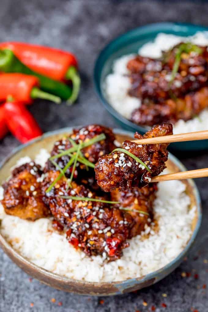 A piece of Chinese Crispy Chicken being picked up with a pair of chopsticks