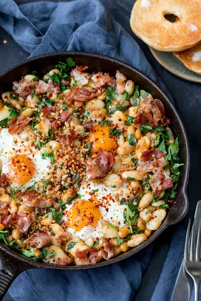 Overhead picture of  Spicy Egg Breakfast with Smashed Beans and Pancetta in a skillet