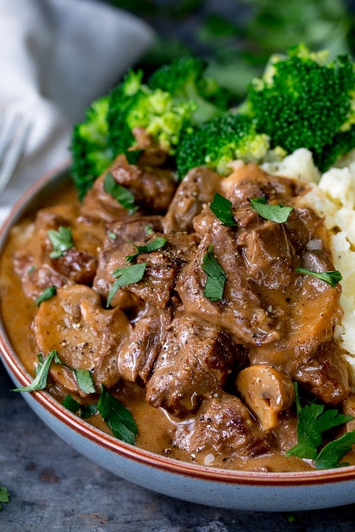 steak diane casserole in a bowl with broccoli