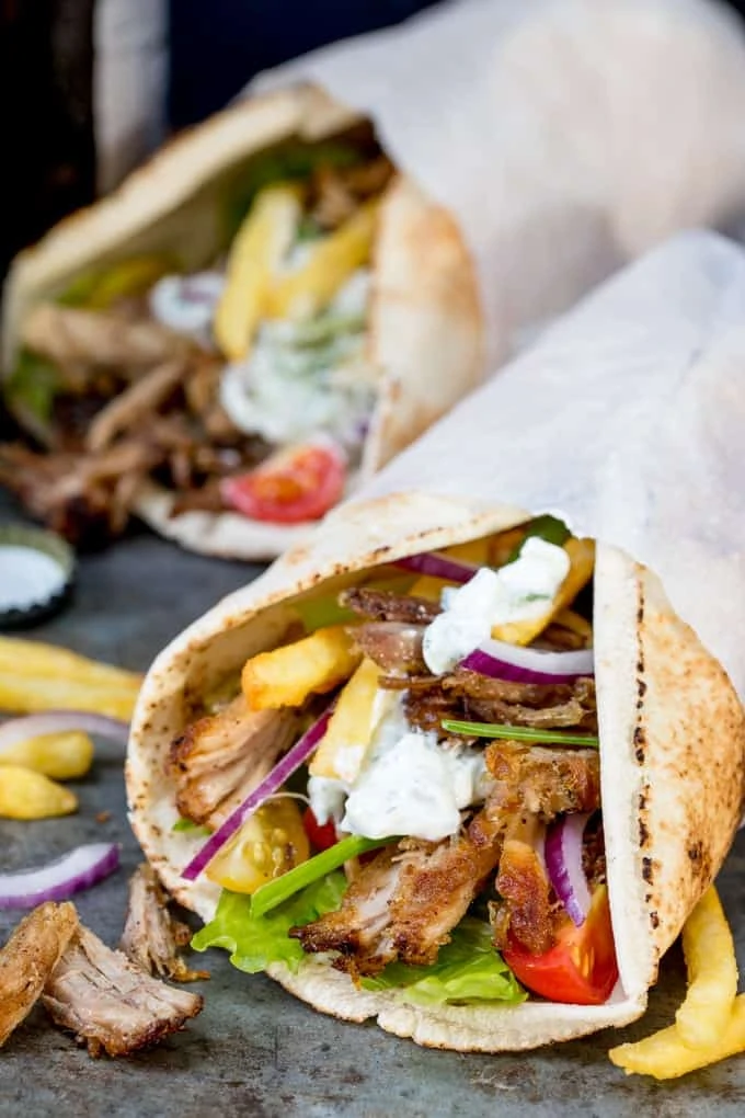 Pork Gyros in a flatbread with sauce and toppings, being held in a hand