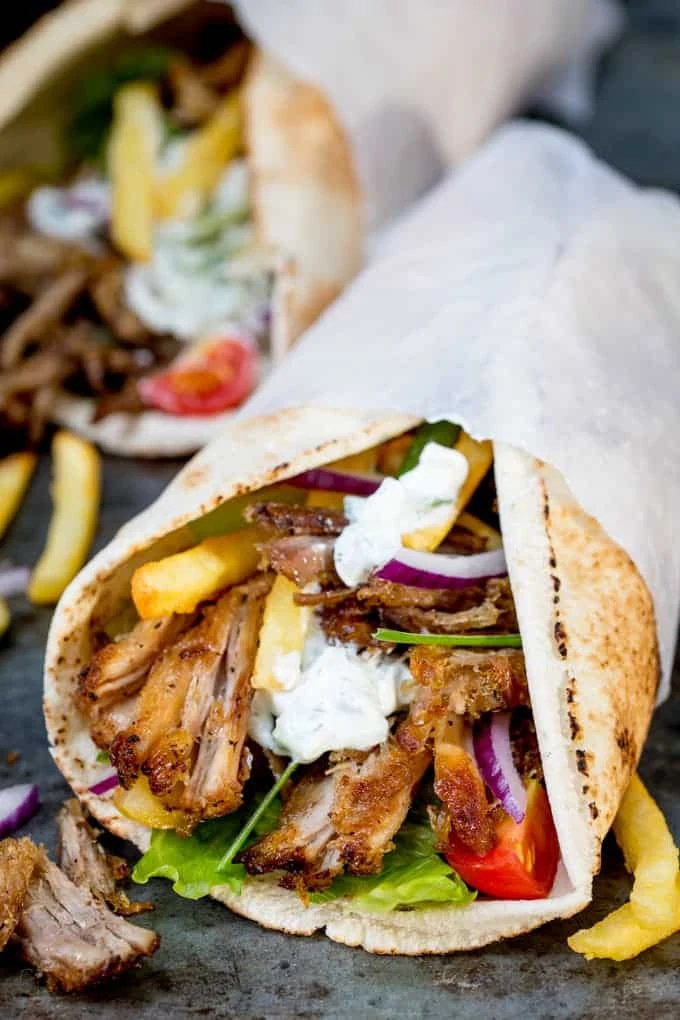 Crispy Pork Gyros with lettuce, tomato, red onion and tzatziki on an open flatbread