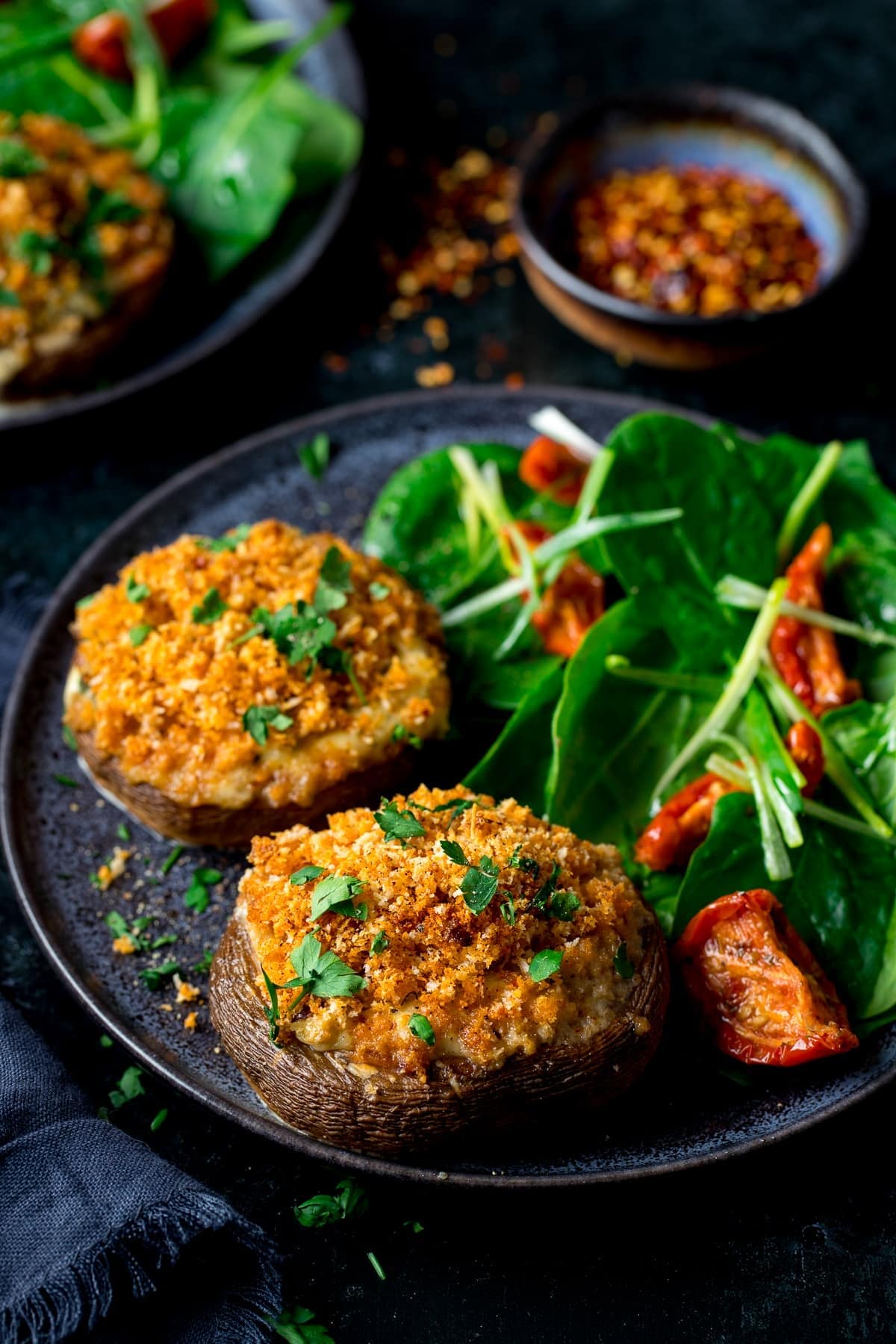 Stuffed mushrooms with salad on a dark plate
