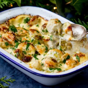 3 cheese sprout gratin, with one sprout being lifted with a spoon.
