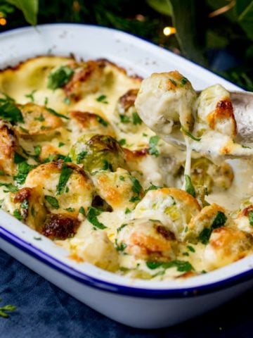 3 cheese sprout gratin, with one sprout being lifted with a spoon.