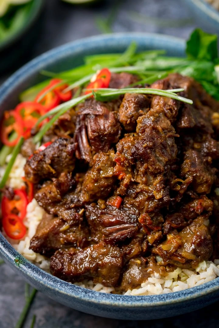 Beef rendang in a blue bowl with rice and chillies