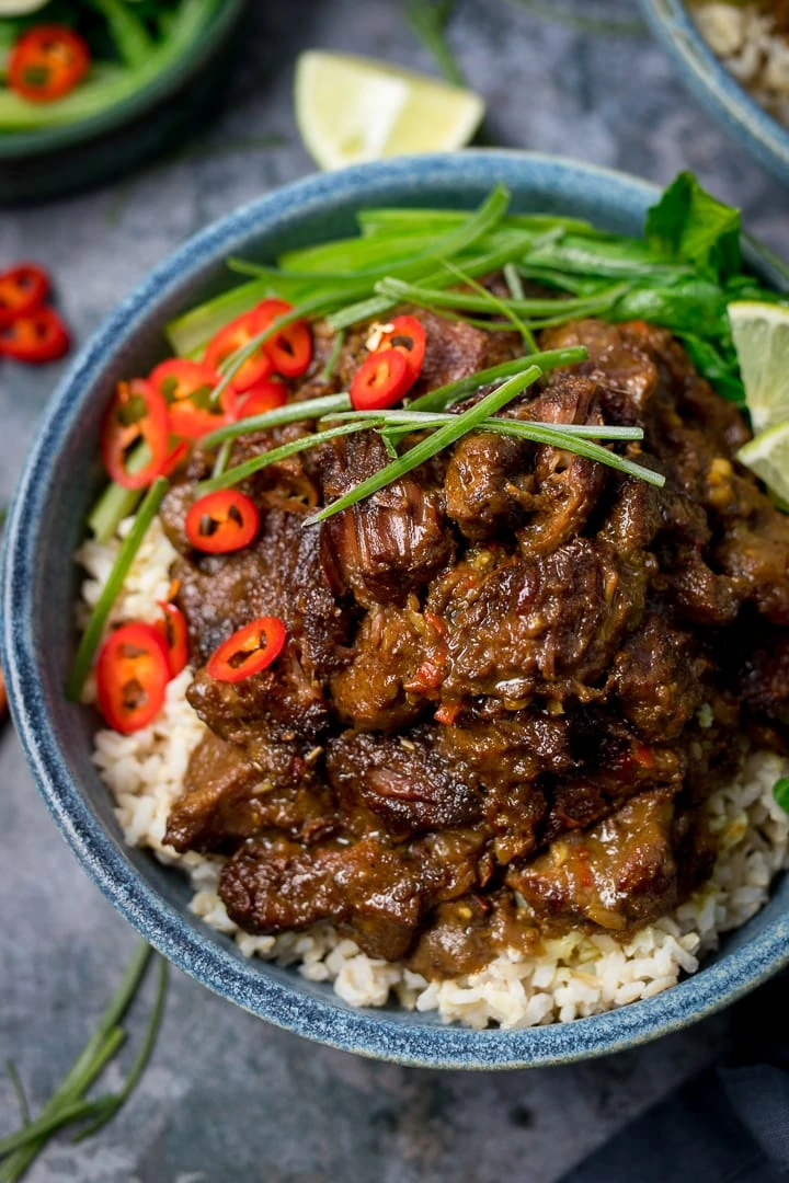 Overhead image of Beef rendang in a blue bowl on rice