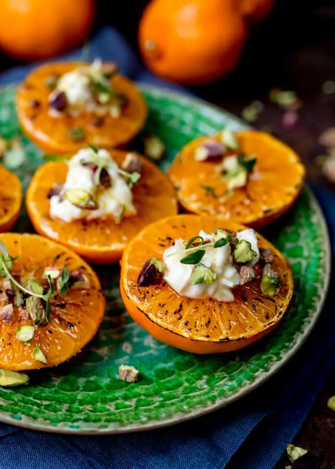 Close up side on photo of Brown Sugar Glazed Clementines with Cream Cheese, Honey and Pistachios on a green plate